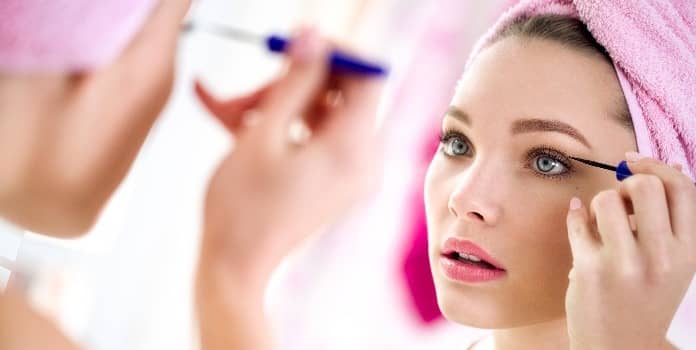 femme qui se met de l'eye liner devant un miroir